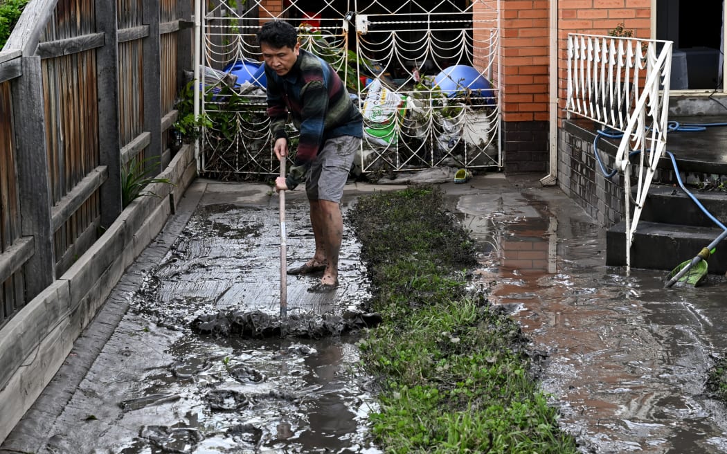 Un hombre limpia el lodo de una propiedad inundada en el suburbio de Maribyrnong en Melbourne el 15 de octubre de 2022.  - La primera víctima mortal de Australia por inundaciones repentinas generalizadas el 15 de octubre de 2022, a pesar de las fuertes lluvias y los altos niveles de inundación.  Sureste.  Cientos de propietarios de viviendas comenzaron una larga limpieza cuando las aguas pluviales inundaron calles, casas y automóviles en tres estados, siendo los suburbios de Melbourne los más afectados.  (Foto de William West/AFP)