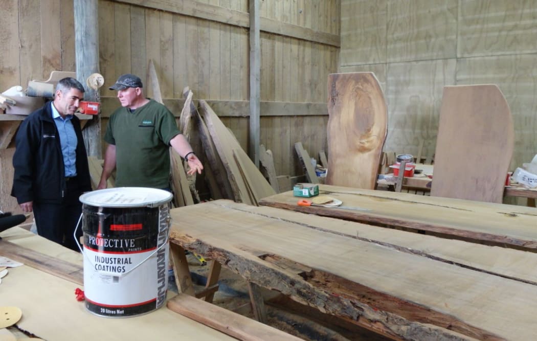 Nathan Guy examines kauri slabs and table tops with Kaihu mill and gallery owner Nelson Parker.