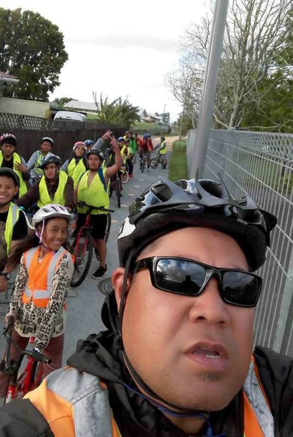 A selfie of a group of children on bikes wearing hi-viz vests. Teau Aitura is in the foreground