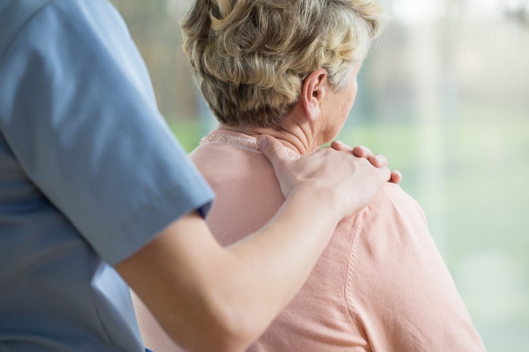 Nurse putting hand on elderly woman's shoulder