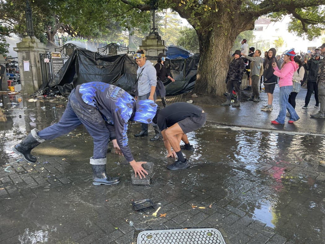 Protesters pull up pavers to throw at police outside Parliament.