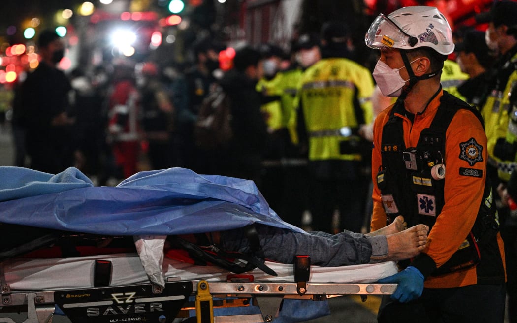 Victims of the Halloween crash that killed at least 120 people are transported on stretchers in the Itaewon district of Seoul, October 30, 2022. Thousands of people swarmed central Seoul as thousands thronged the narrow streets to celebrate Halloween, officials said.  (Photo by Anthony Wallace/AFP)