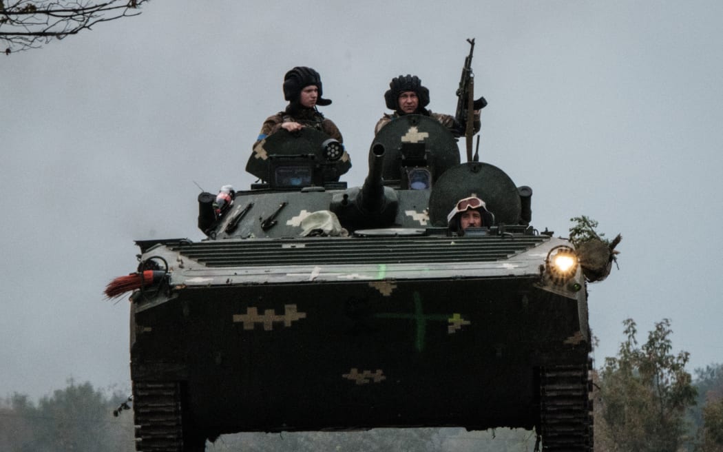 Des soldats ukrainiens conduisent un véhicule blindé de transport de troupes (APC) à Kobiansk, dans la zone nouvellement reprise près de Kharkiv, le 30 septembre 2022.
