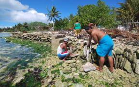 People of Kiritimati coral atoll building a stone seawall to struggle against sea level rise cause by global warming.