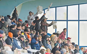 Thistle fans in the stand at Childers Road Reserve take to their feet to cheer on their players.
