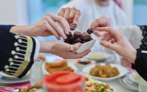 Muslim family having iftar together during Ramadan. Arabian people gathering for traditional dinner during fasting month. Dates sharing to break fasting
