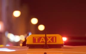 Taxi sign on the roof of the car on a blurred background in red evening light.