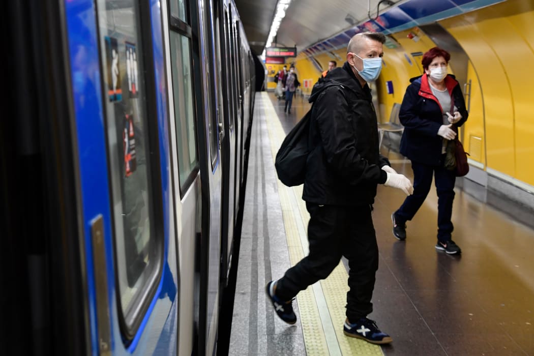 Commuters wearing face masks arrive at the Atocha Station in Madrid on April 13, 2020 as some companies were set to resume operations at the end of a two-weeks halt of all non-essential activity amid a national lockdown to stop the spread of the COVID-19 coronavirus.