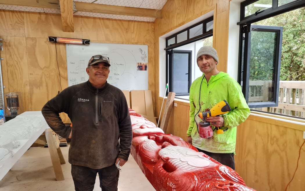 Tipene Kawana (left) standing in the carving studio with the carvings for the new wharenui.