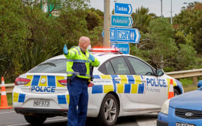 A police officer directs a driver wanting to leave the city at a COVID-19 check point setup at the southern boundary in Auckland on August 14, 2020.