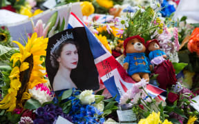 LONDON, UNITED KINGDOM - SEPTEMBER 11: A portrait of Queen Elizabeth II is placed next to Union Jack flag and Paddington bears among flowers as crowds of people visit a memorial site in Green Park on the third day of national mourning following the death of Queen Elizabeth II in London, United Kingdom on September 11, 2022. Queen Elizabeth II, Britain's longest reigning monarch, has died peacefully at the age of 96 at Balmoral Castle on Thursday after 70 years on the throne. Wiktor Szymanowicz / Anadolu Agency (Photo by Wiktor Szymanowicz / ANADOLU AGENCY / Anadolu Agency via AFP)