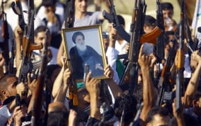 Iraqi Shiite tribesmen brandish a poster of Shiite cleric Grand Ayatollah Ali al-Sistani as they show their willingness to join Iraqi security forces in the fight against Jihadist militants.