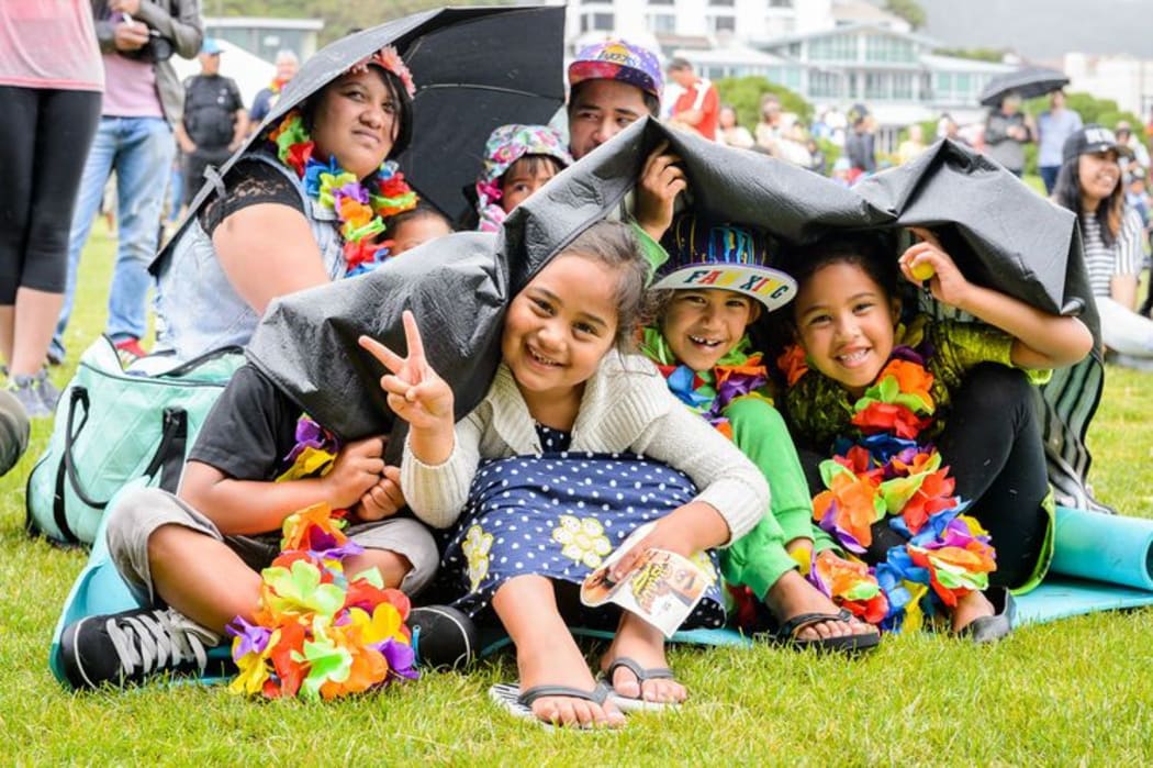 Happy kids in bright clothing under umbrellas