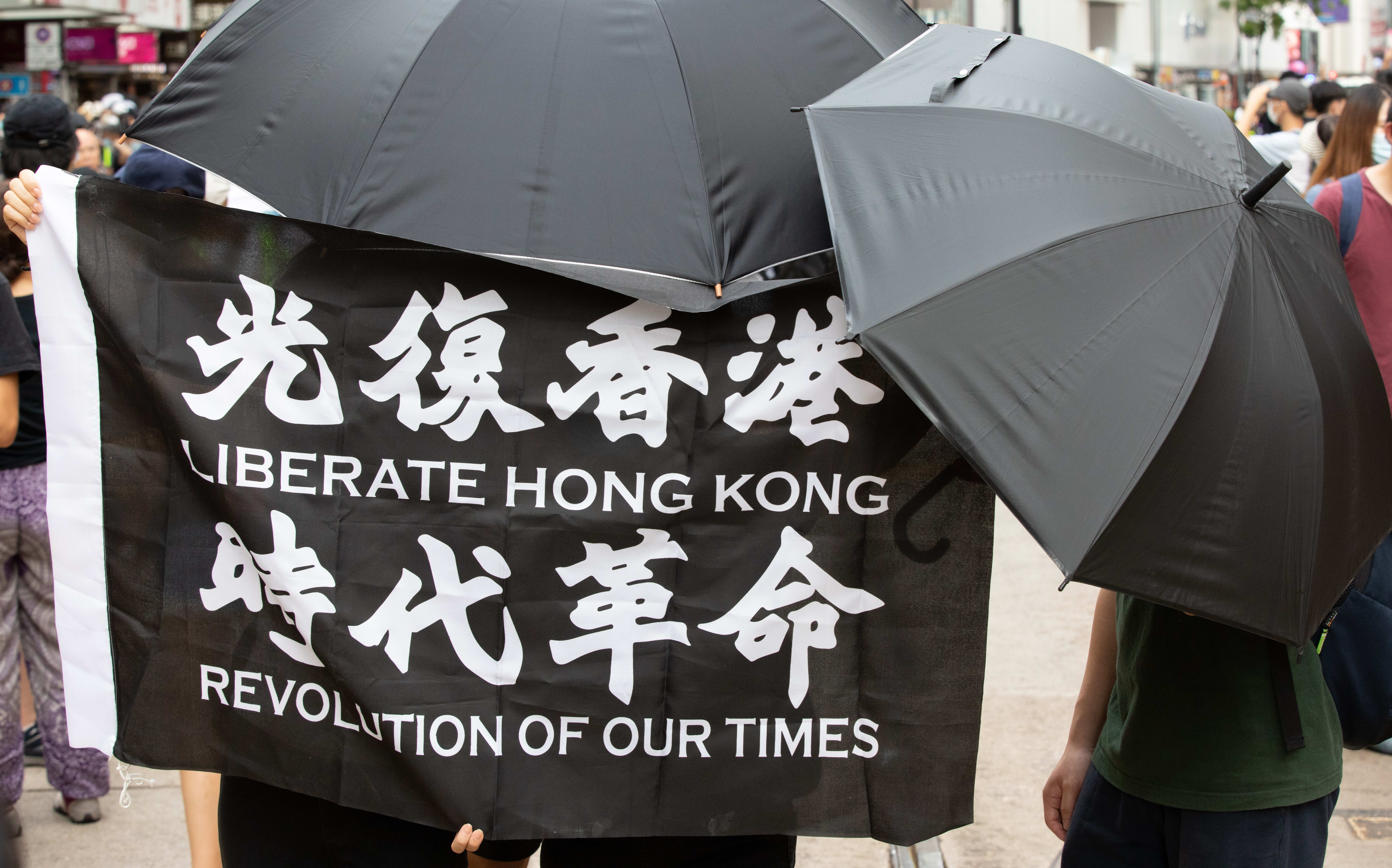 Protesters hold a "Liberate Hong Kong, Revolution of our times" flag while covering their face due to the now introduced National Security Law in Hong Kong, China, on July 1, 2020.
