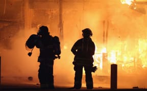Firefighters try to extinguish a burning restaurant, set alight by protestors angered by the decision not to charge the police officer who shot Michael Brown.