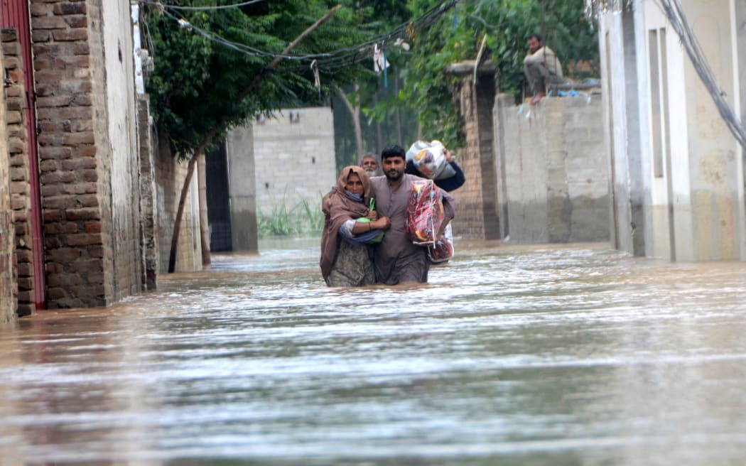 PESHAWAR, PAKISTAN - AUGUST 27: Displaced people wade through a flooded area in Peshawar, Khyber Pakhtunkhwa, Pakistan on August 27, 2022. Since June, nearly 900 people have died by severe monsoon rains and floods in Pakistan, while thousands have been displaced and millions more affected. Thousands of people who live in areas under threat of flooding have been told to evacuate. Hussain Ali / Anadolu Agency (Photo by Hussain Ali / ANADOLU AGENCY / Anadolu Agency via AFP)