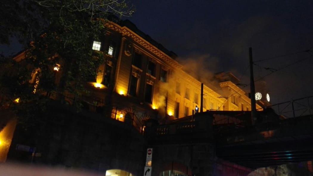 Smoke billows out of Sydney's Central Railway Station, lit by yellow lights.