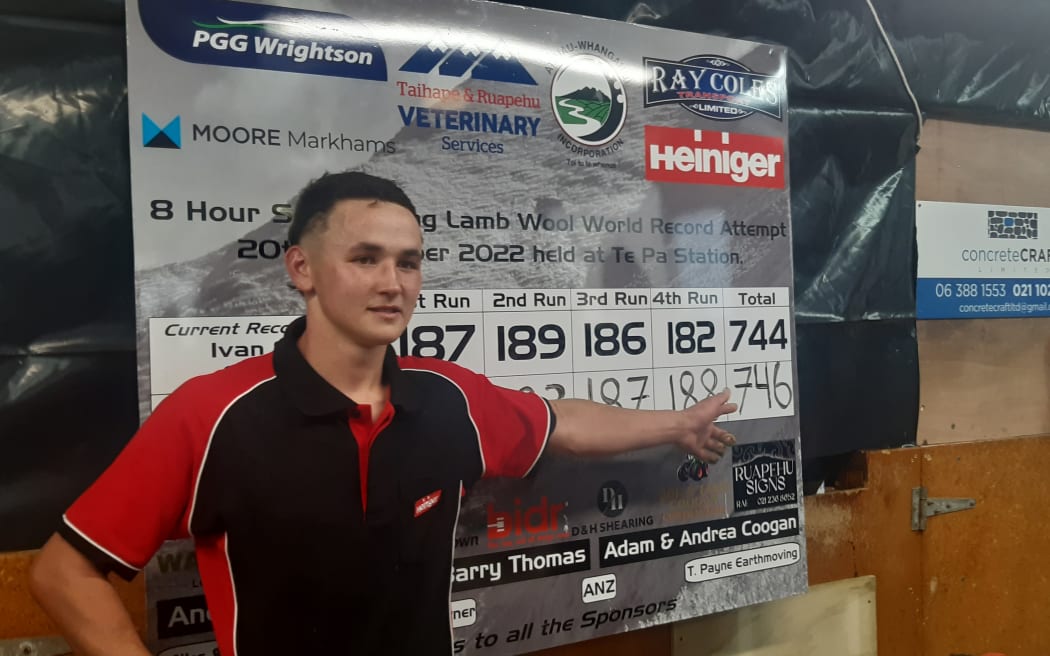 Reuben Alabaster, 19, points to a board showing his world-record tally of 746 lambs shorn in eight hours.