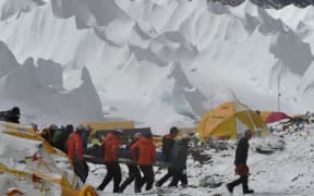 Rescue team personnel carry an injured person towards a waiting rescue helicopter at Everest Base Camp.