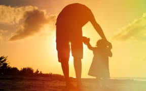 Father and child silhouette on beach generic