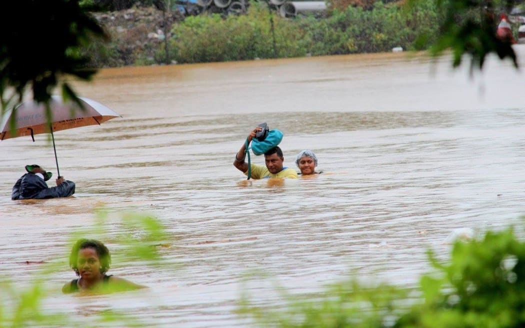 Residents of Korociri settlement cross through the flooded Nadi backroad.
