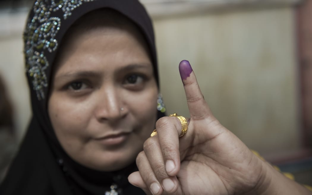 A Muslim Myanmar voter poses with her inked finger after she cast her vote at a polling station in Yangon.