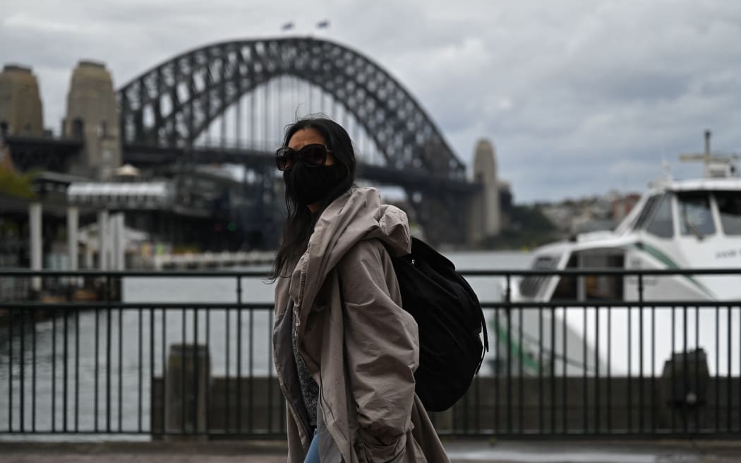 A woman walks past the Sydney Harbour Bridge after stay-at-home orders were lifted across NSW, in Sydney, Australia, Tuesday, October 12, 2021.