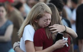 People hug as they attend a candlelight memorial service for the victims of the shooting at Marjory Stoneman Douglas High School that killed 17 people on February 15, 2018 in Parkland, Florida.