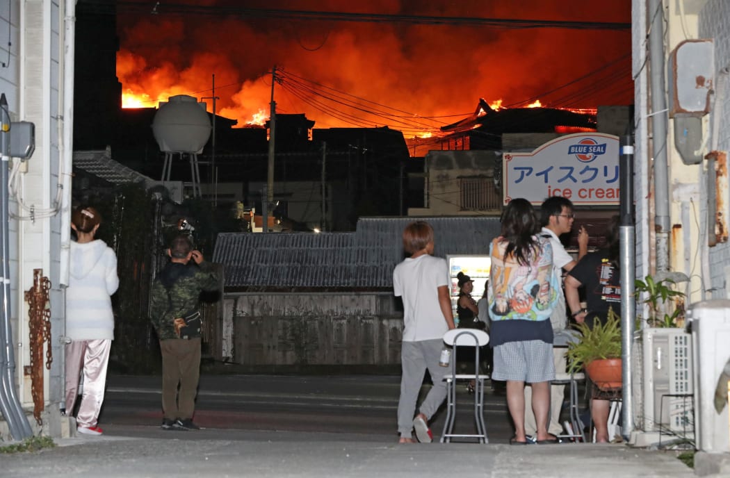 People watch the World Heritage Shuri castle on fire in Naha.