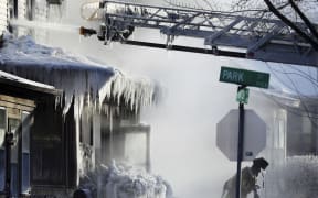 Firefighters at the scene of a house fire in Saint Paul, Minnesota during a arctic deep freeze on 30 January.