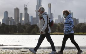 People walk along Albert Park lake in Melbourne on July 13, 2020, as five million people in Australia's second-biggest city began a new lockdown following a resurgence of coronavirus cases.