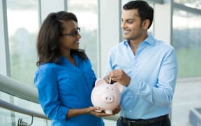 77306946 - closeup portrait, two smart professionals in blue shirts holding piggy bank, isolated office indoors background. powerful financial and banking business solutions, decisions concept