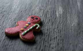 closeup of a sad gingerbread man on a rustic wooden surface, with a negative space