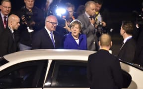 Germany's Chancellor Angela Merkel (C) is welcomed upon her arrival at the airport in Brisbane to take part in the G20 summit on 14 November 2014.