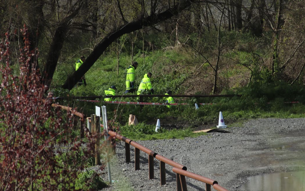 Police around the banks of the Tukituki River near Havelock North, near where a burnt-out car was found.