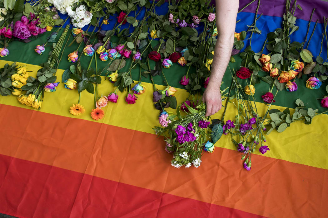 Demonstrators lay roses on a rainbow flag as they protest over a 2017 alleged crackdown on gay men in Chechnya outside the Russian Embassy in London.