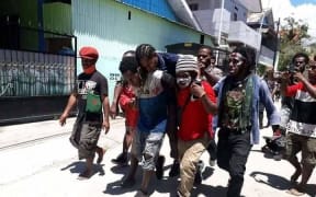 West Papuan students carry a wounded fellow demonstrator after security forces came to disband their rally, Waena, 27 October, 2020