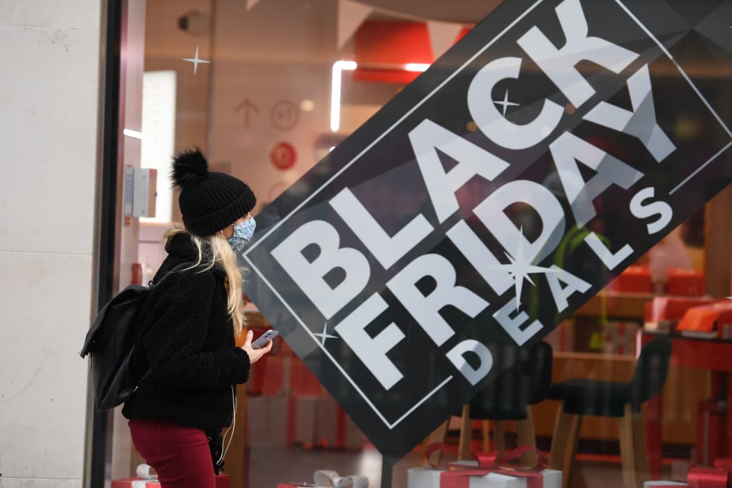 A pedestrian wearing a mask because of the novel coronavirus pandemic walks past a shop advertising Black Friday sales on Oxford Street in London on November 26, 2020.