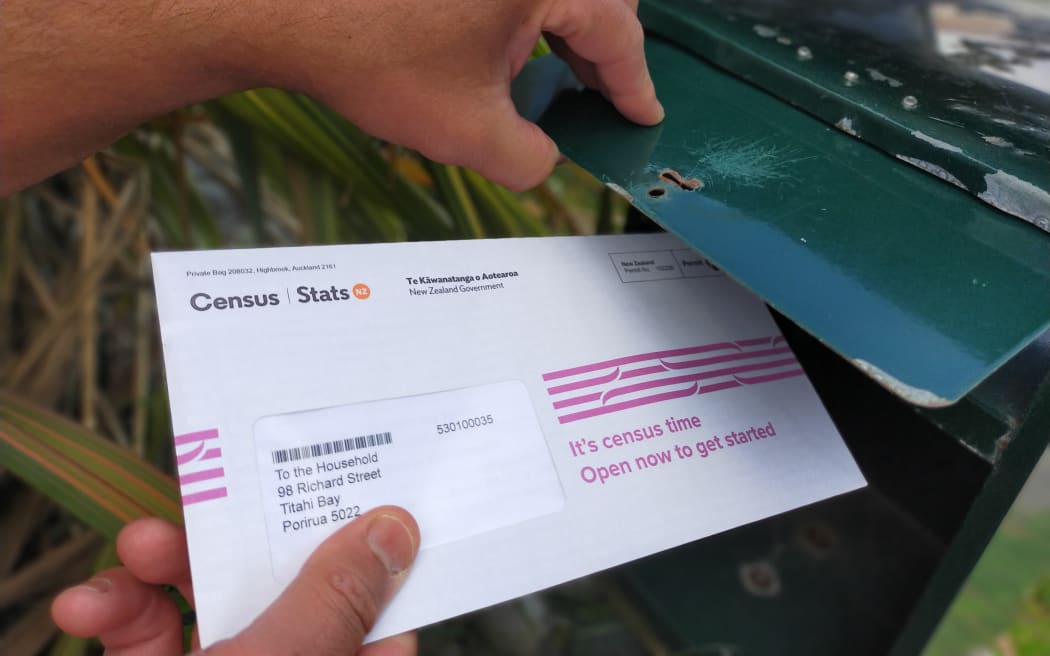 A Census 2023 ltter being removed from a letterbox.