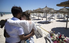 People react at the site of a shooting attack on the beach in front of the Riu Imperial Marhaba Hotel.