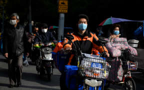 Motorists wearing face masks, amid concerns over the spread of the COVID-19 novel coronavirus, commute along a street in Shanghai on March 23, 2020.