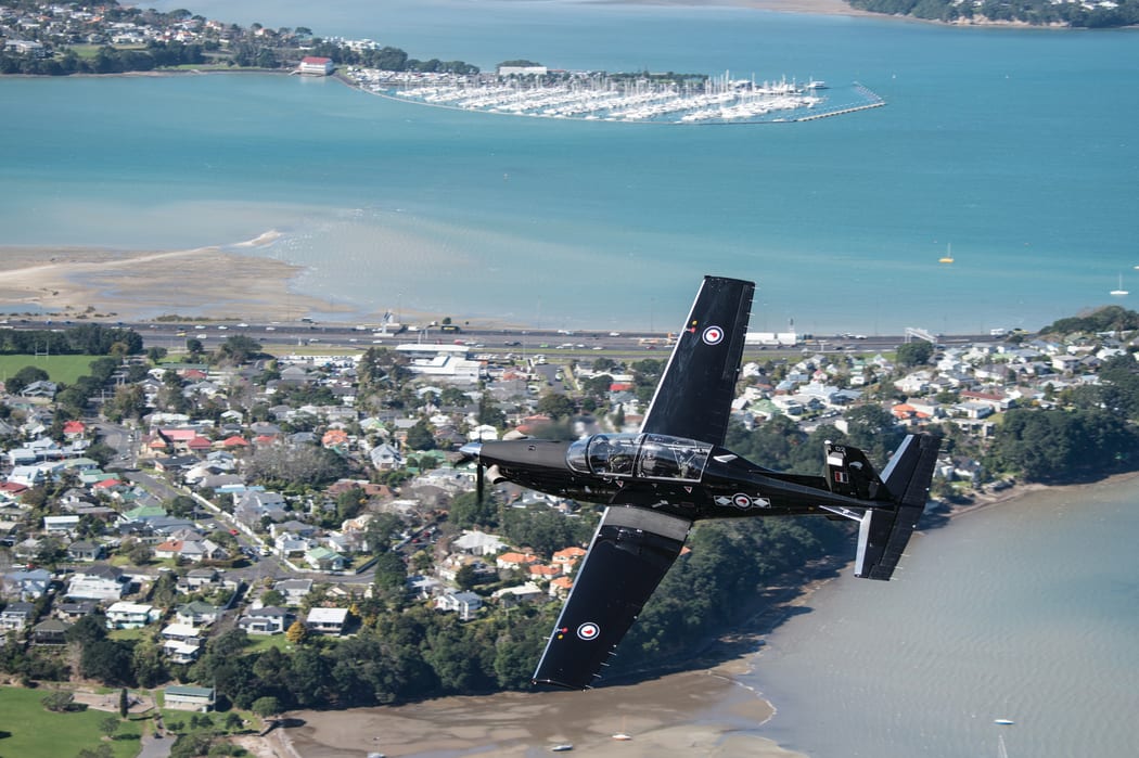 RNZAF plane flying over a costal community.