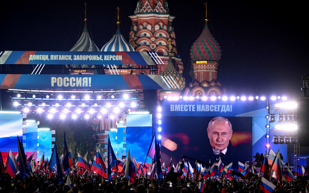 Le président russe Vladimir Poutine est vu sur un écran sur la Place Rouge, dans le centre de Moscou, le 30 septembre 2022, alors qu'il s'adresse à un rassemblement et à un concert marquant l'annexion de quatre régions d'Ukraine occupées par les troupes russes - Lugansk, Donetsk, Kherson et Zaporizhzhia.