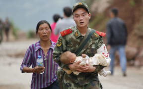 A rescuer carries a baby after a deadly earthquake hit in China's Yunnan province.