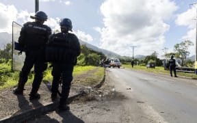 Police officers guard the road in Mont-Dore, to the south of New Caledonia's capital, Noumea. The road is frequently closed by armed protesters.