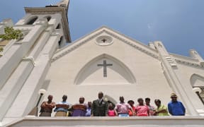 Members of the historic Emanuel African Methodist Church stand in front of the church and announce that services and Sunday school will go ahead as scheduled on Sunday.