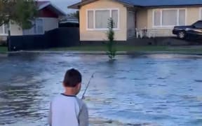 Jamie Lindsay's son fishing in their flooded street in Pirimai, Napier