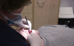 A dentist performs dental work.