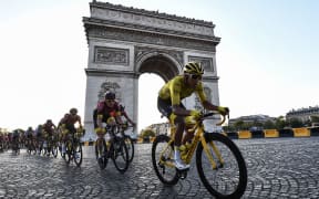 Colombia's Egan Bernal (R), wearing the overall leader's yellow jersey (C-R) and cyclists ride down the Champs Elysees avenue next to the Arc de Triomphe during the 21st and last stage of the Tour de France in Paris, on July 28, 2019.