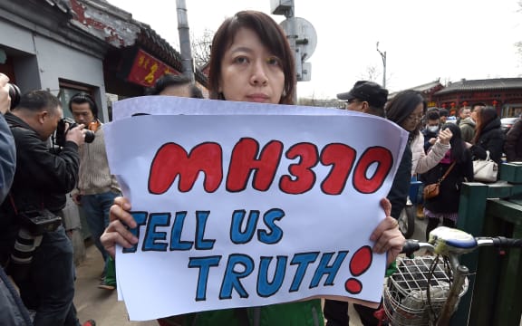 A family member of a Chinese passenger from the missing Malaysia Airlines flight MH370 shows a poster as she leaves after a prayer session at the Yonghegong Lama temple in Beijing.